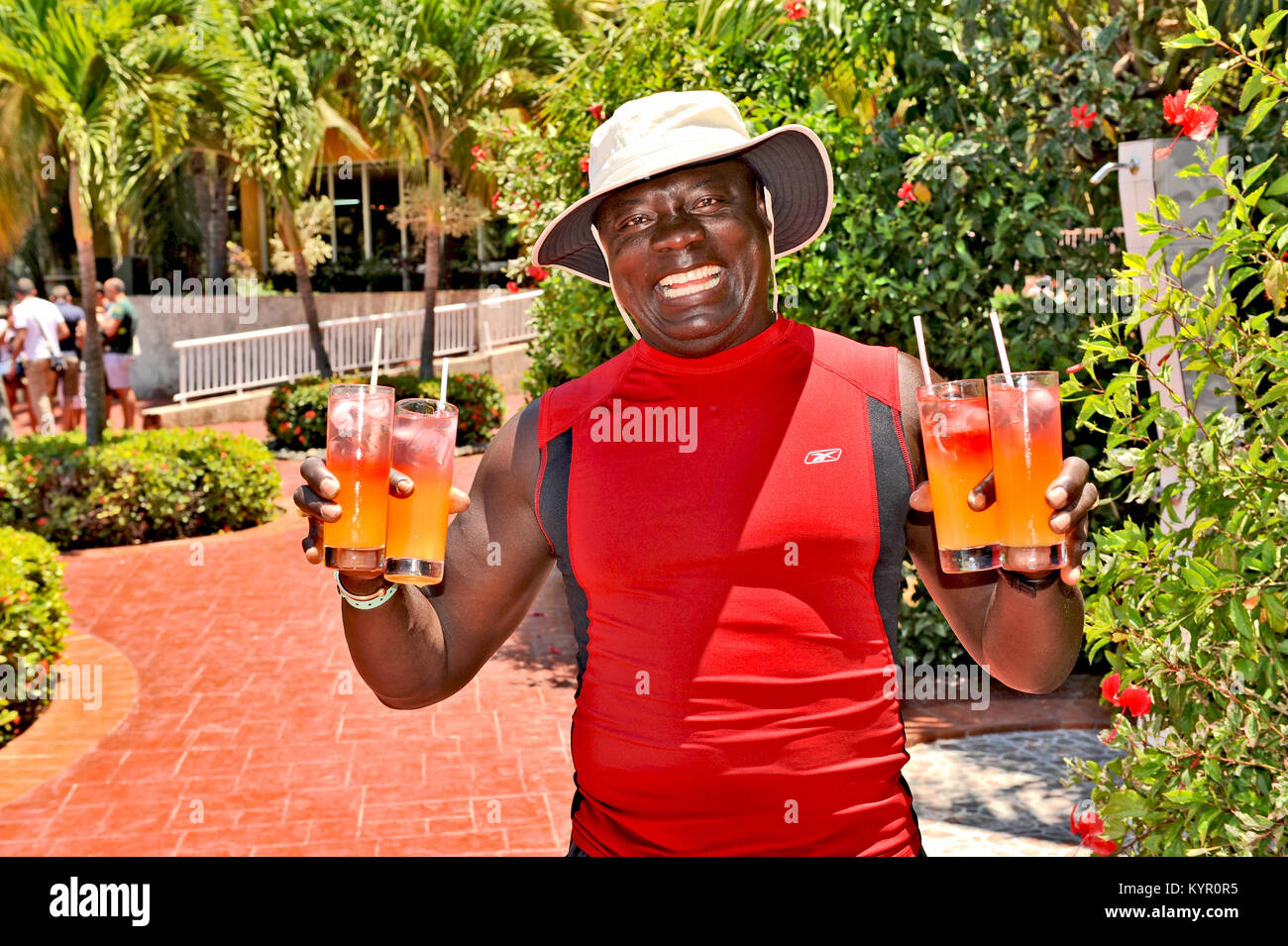HAVANA, CUBA, MAY 5, 2009. A smiling man in a diving suit holding four fruit coctails in his hands, in Havana, Cuba, on May 5th, 2009. Stock Photo