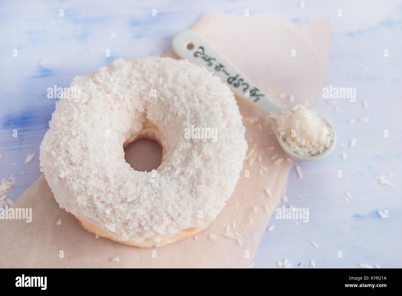 Close-up of a white donut with coconut topping on a light background. High key food photography. Stock Photo