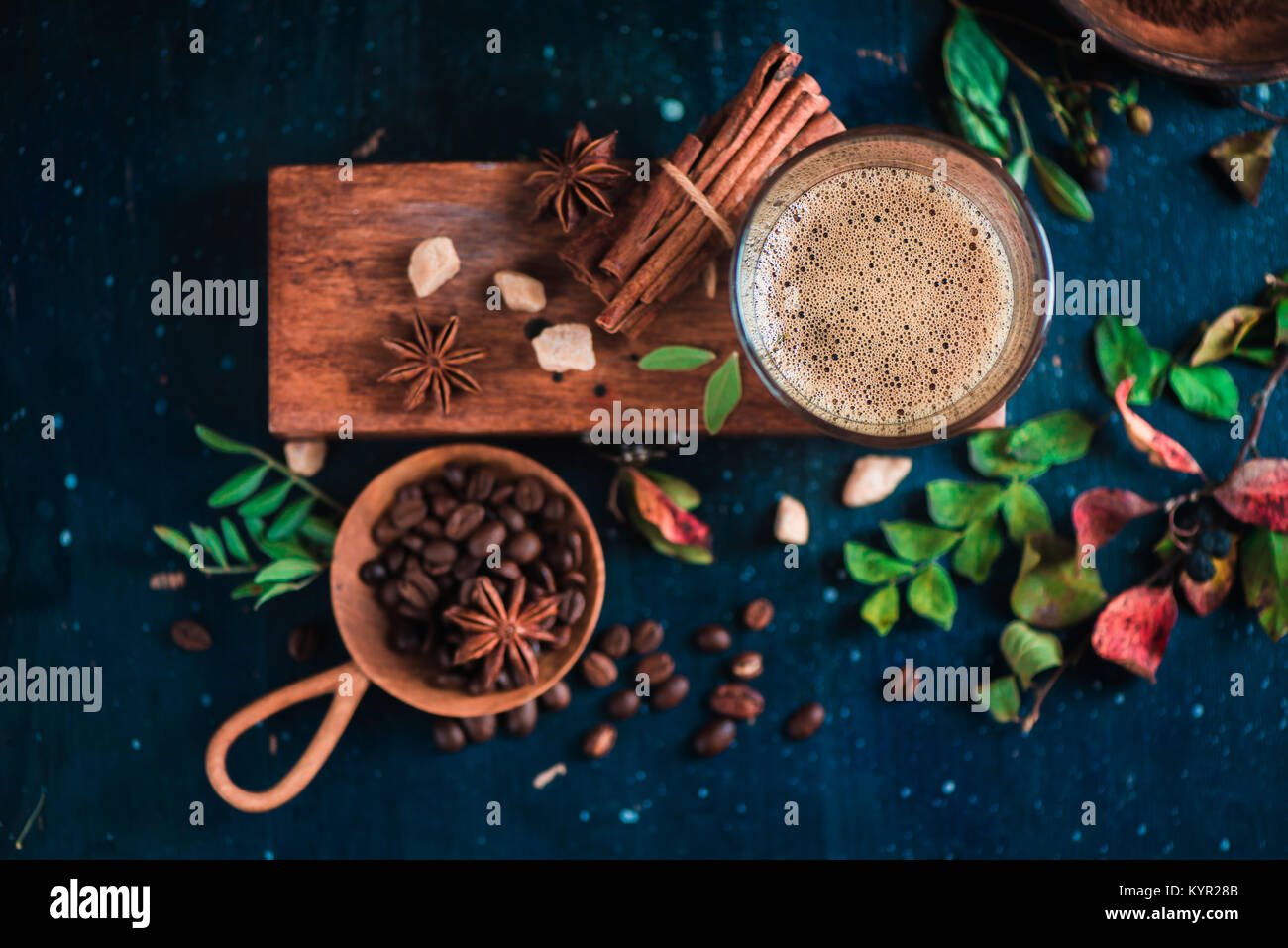 Flat lay with espresso shot with foam on a wooden box, coffee beans, arabica leaves, cinnamon and spices on dark background. Hot drink photography con Stock Photo