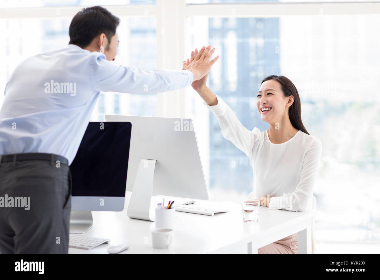 Confident business people high fiving in office Stock Photo - Alamy