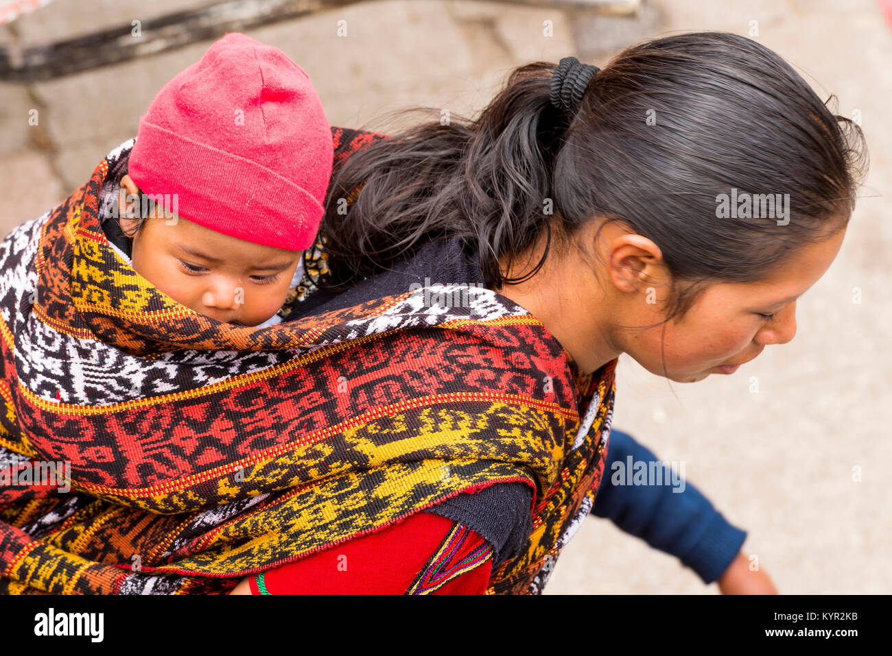 SAN JUAN OSTUNCALCO, GUATEMALA - JUNE 24: An unidentified baby carried in a traditional woven material sling on a womans back at the San Juan Ostuncal Stock Photo