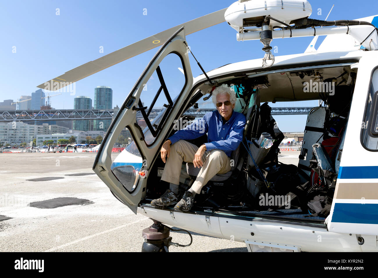 Senior man sitting in the pilot seat of a helicopter on the ground. Open door. Stock Photo