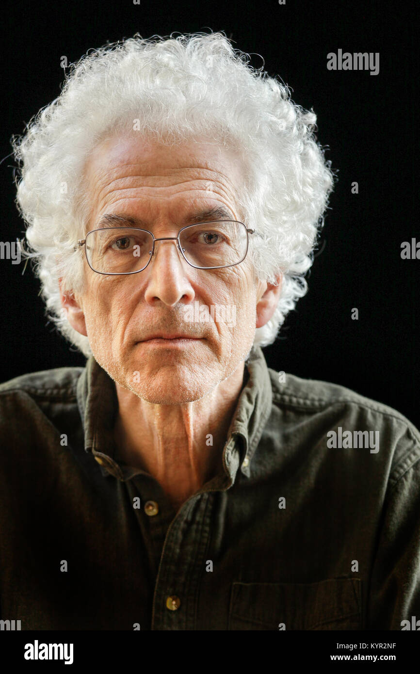 Portrait of an older man with curly white hair looking at camera.  Intense gaze. Black background. Stock Photo