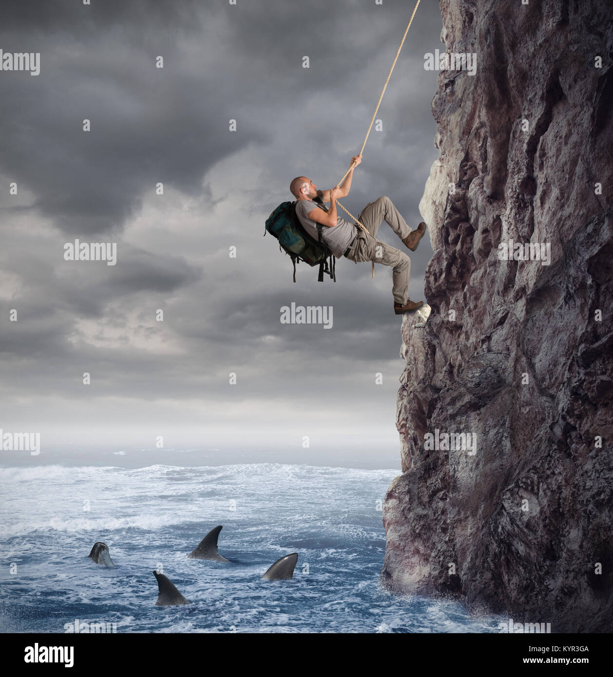 Explorer climbs a mountain with the risk to fall on the sea with sharks Stock Photo