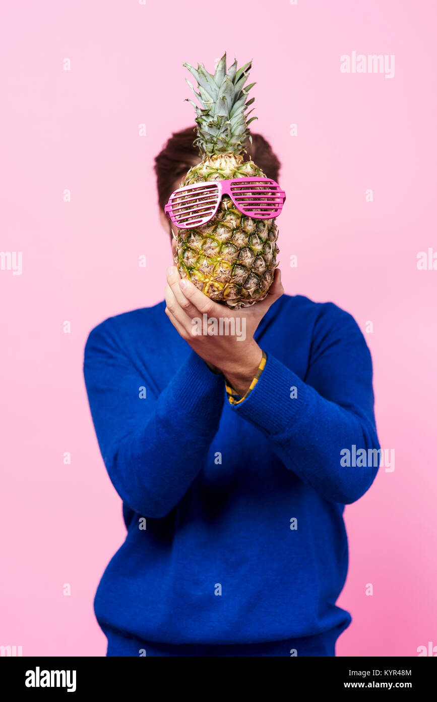 Man holding a pineapple in front of his face Stock Photo