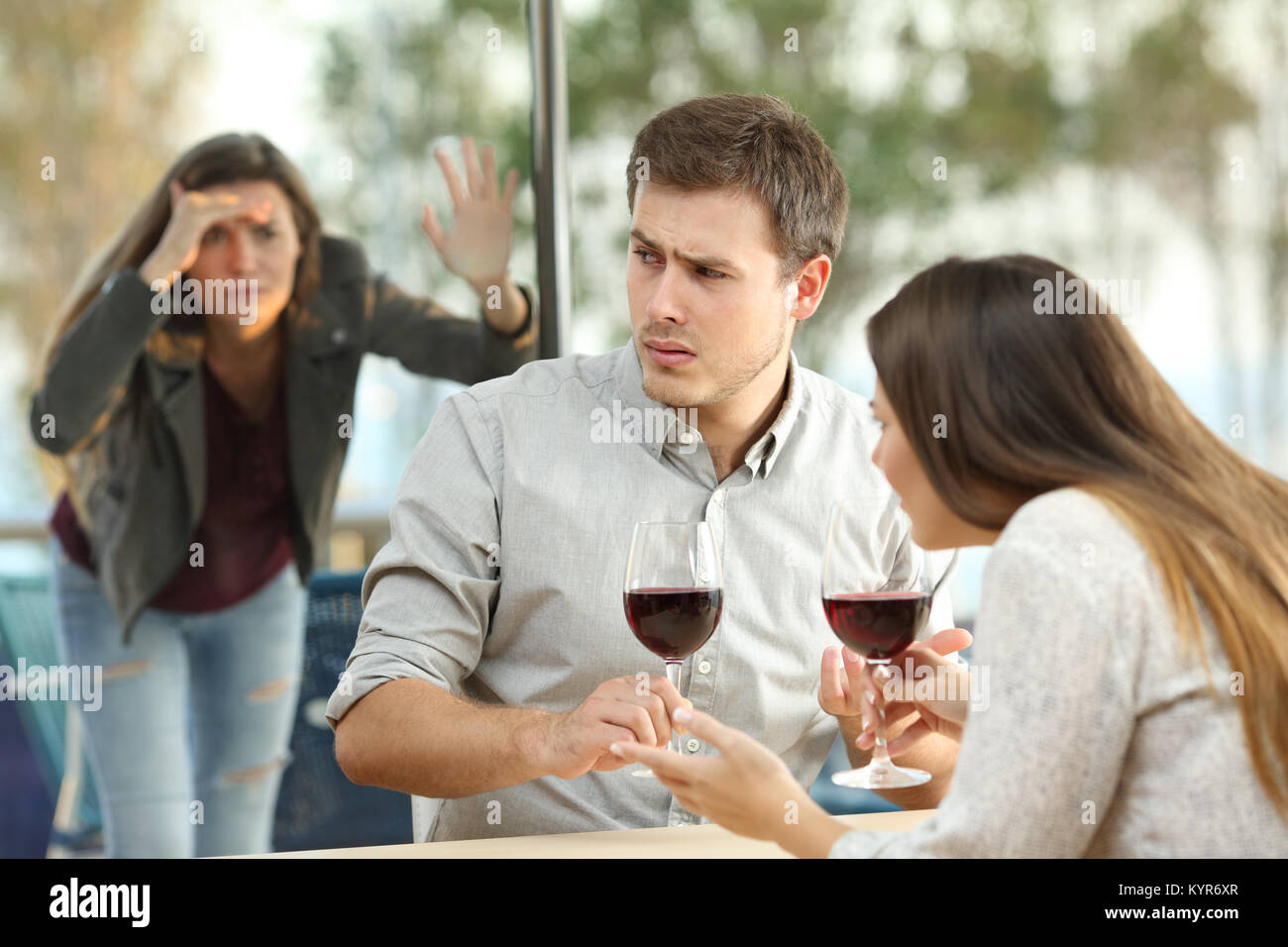 Obsessed ex girlfriend spying on an annoyed couple dating in a restaurant Stock Photo