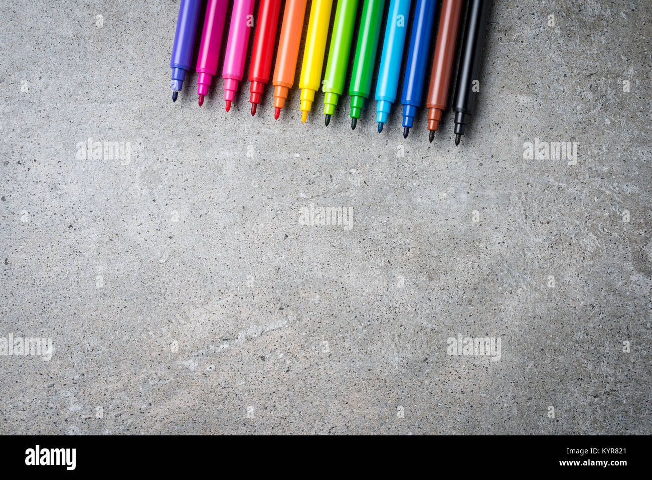 Overhead shot of colorful markers on gray stone table. Close up Stock Photo