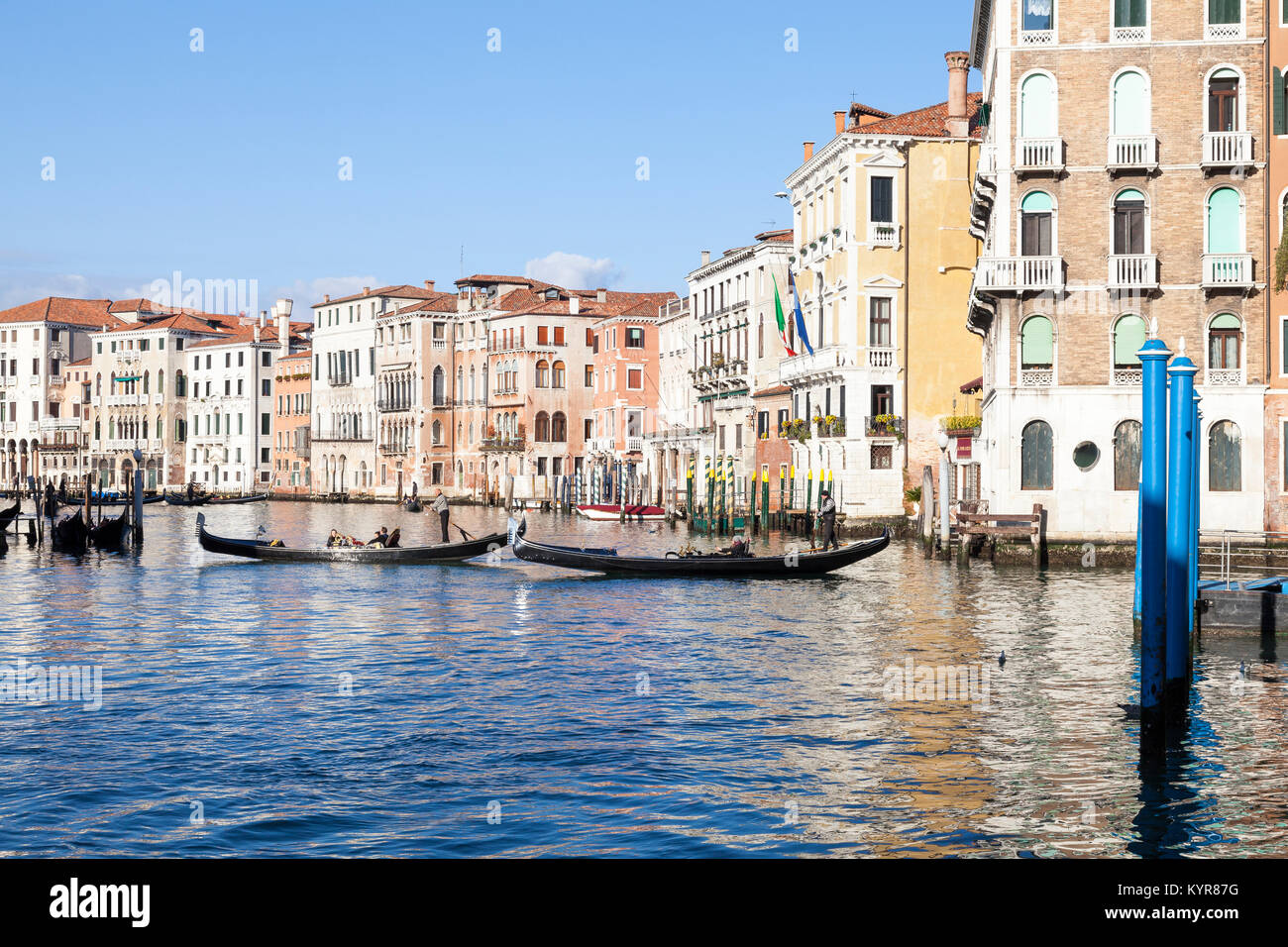 Gondolas with tourists sightseeing on the Grand Canal, Venice,  Veneto, Italy, with reflections from the palazzos on the water in winter sunshine Stock Photo