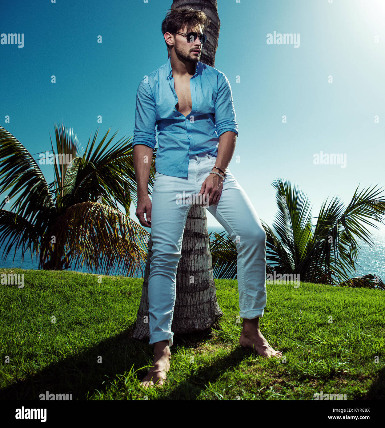 Portrait of a handsome man posing nex to the palm tree Stock Photo - Alamy