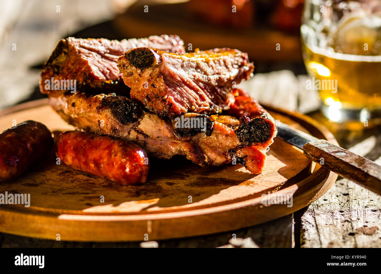 Barbecue pork ribs and sausages with beer on wooden board Stock Photo