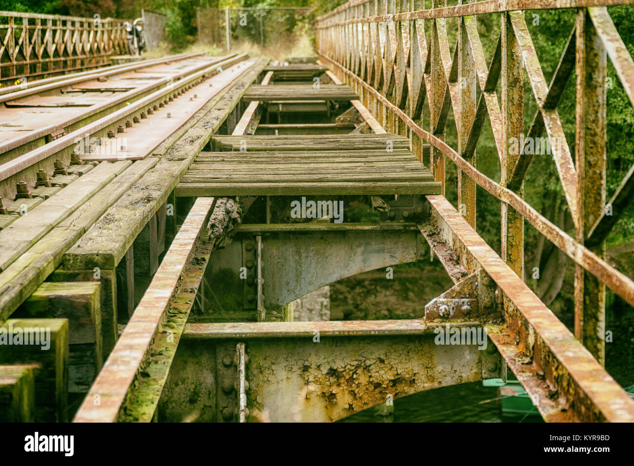 Old abandoned railroad bridge above river in Poland; vintage motorbike in background. Vintage industrial landscape Stock Photo