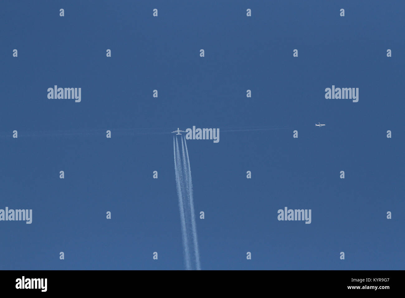 Two jets flight paths crossing high in a blue sky. Stock Photo