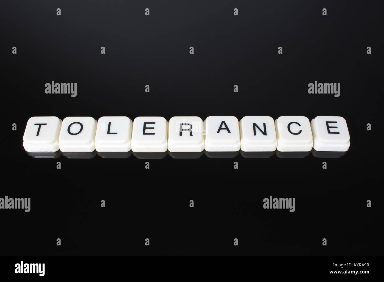 Tolerance text word title caption label cover backdrop background. Alphabet letter toy blocks on black reflective background. White alphabetical letters. White educational toy block with words on mirror table. Stock Photo