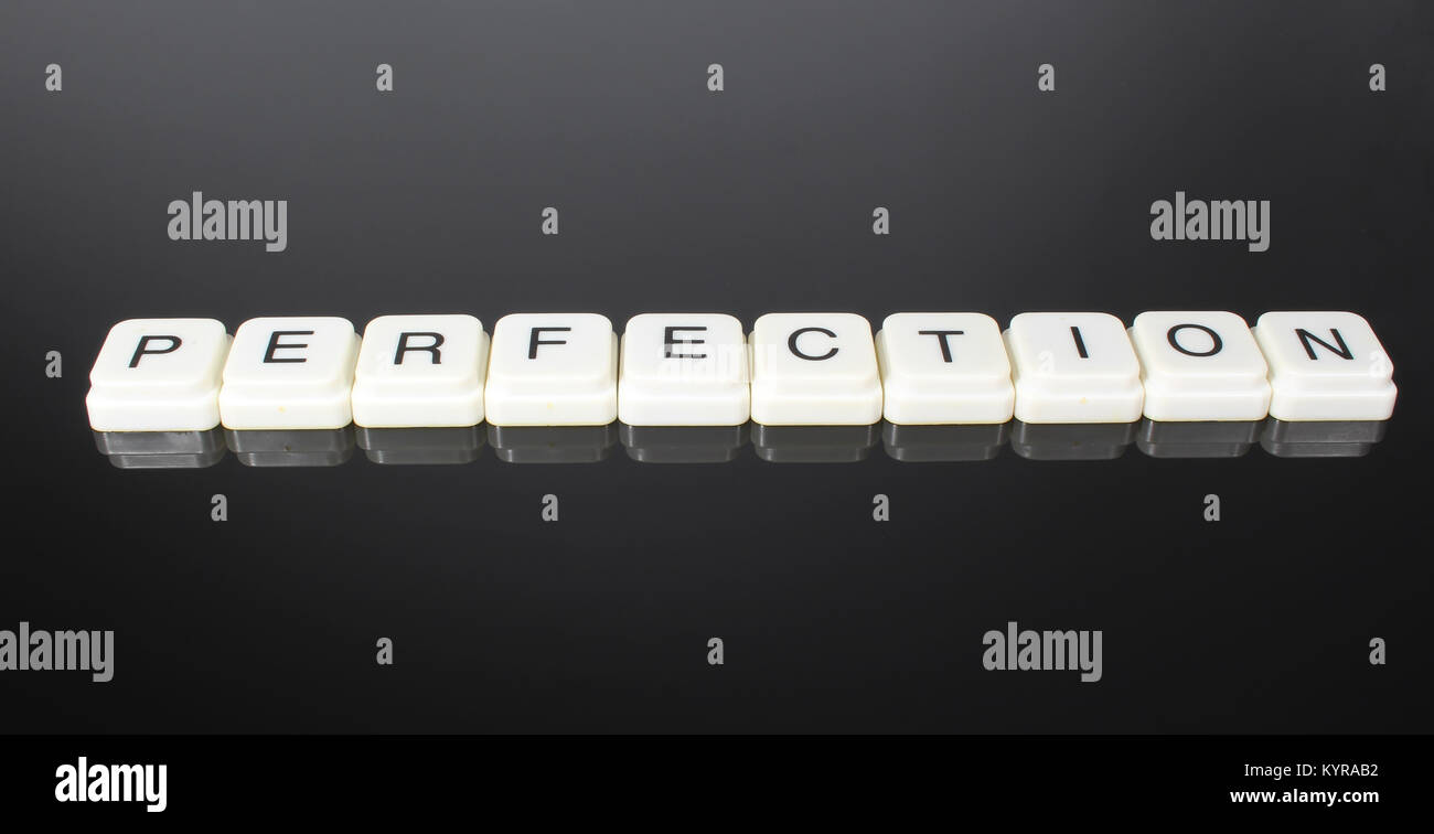 Perfection text word title caption label cover backdrop background. Alphabet letter toy blocks on black reflective background. White alphabetical letters. White educational toy block with words on mirror table. Stock Photo
