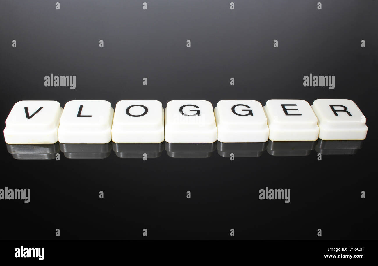 Vlogger text word title caption label cover backdrop background. Alphabet letter toy blocks on black reflective background. White alphabetical letters. White educational toy block with words on mirror table. Stock Photo
