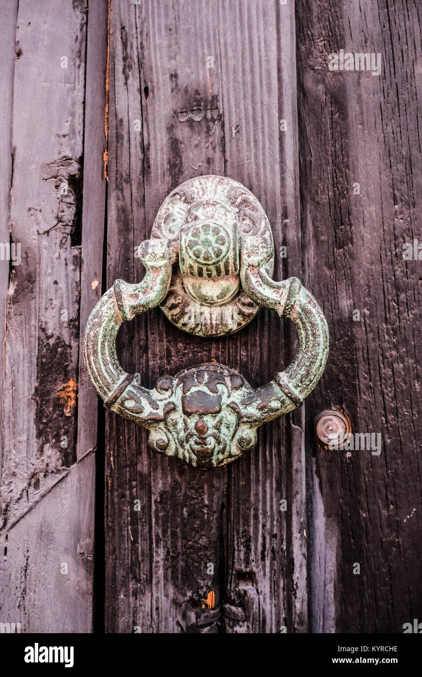 An ornament metal door knocker on an age wooden door in San Miguel de