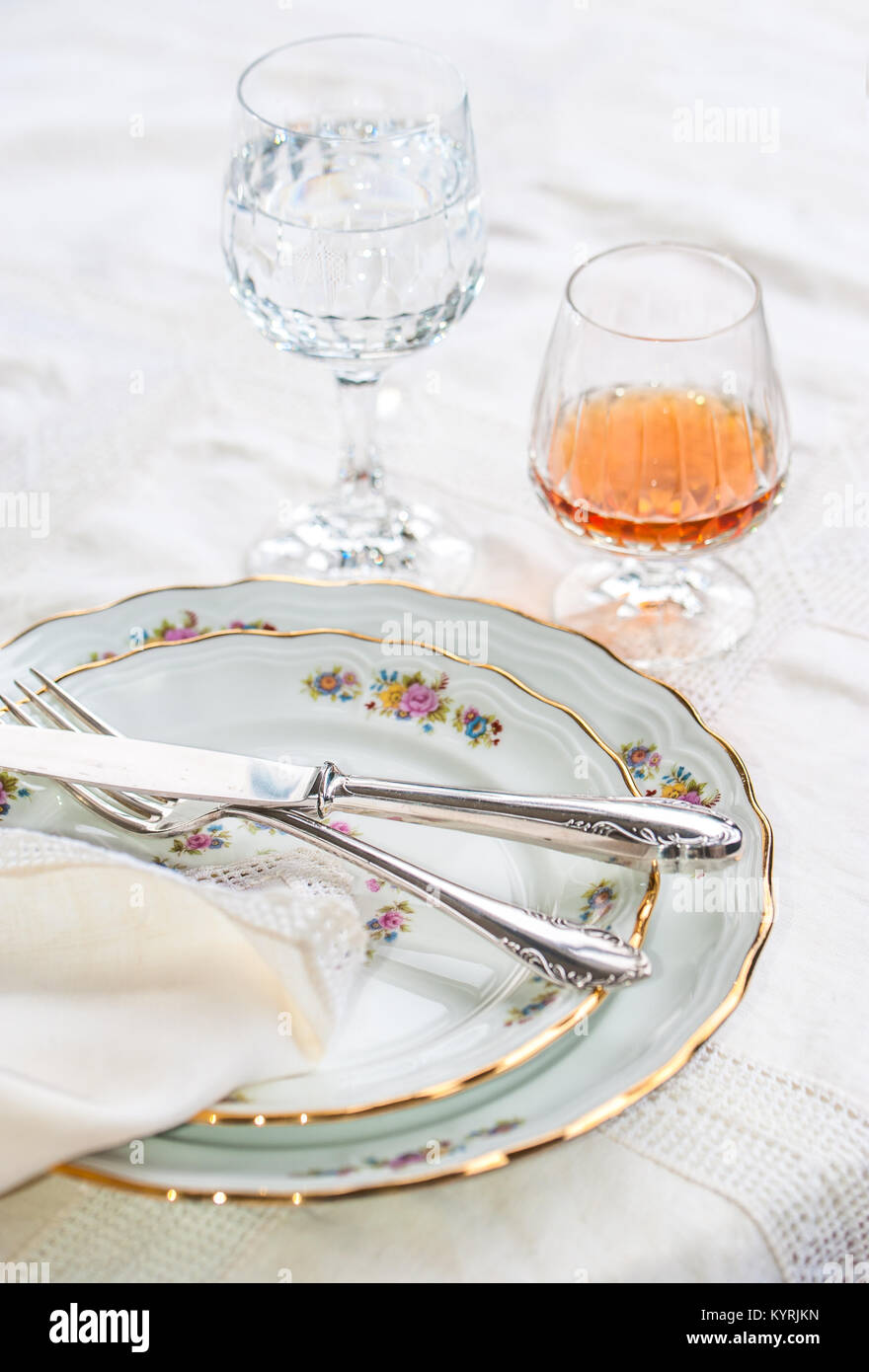 Luxury porcelain dishes, silverware lying across the dishes, crystal