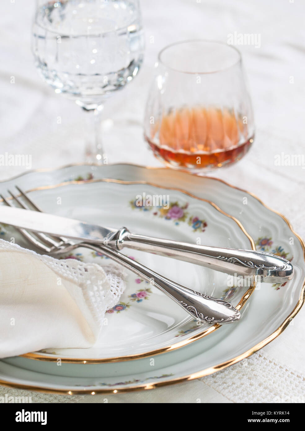 Luxury porcelain dishes, silverware lying across the dishes, crystal