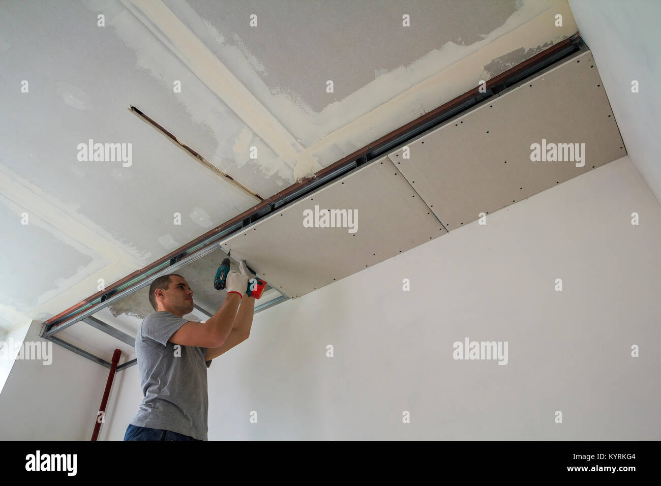 Construction Worker Assemble A Suspended Ceiling With Drywall And