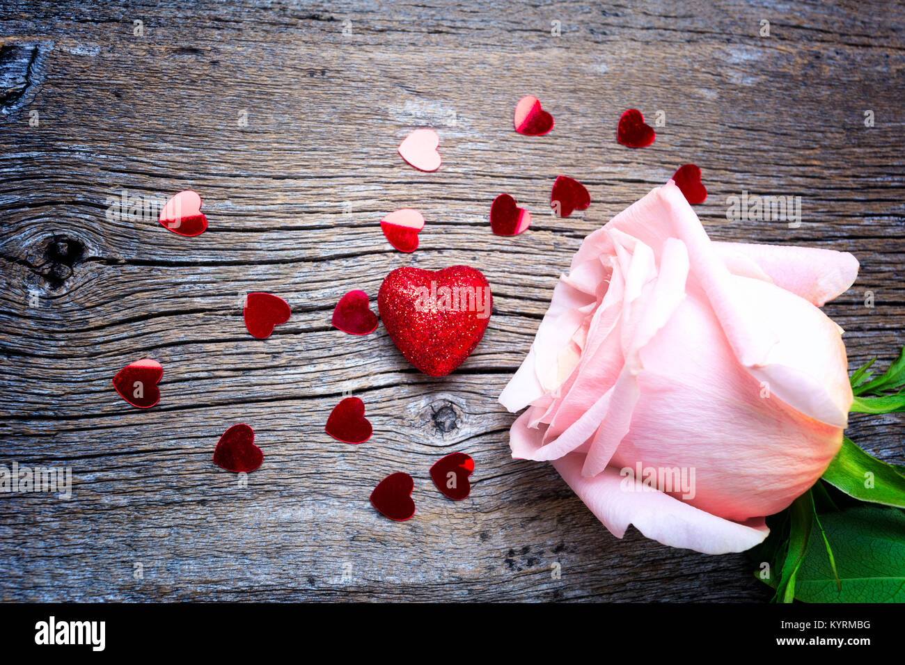 Valentines Day concept with pink roses and red glitter hearts on the rustic wooden background Stock Photo