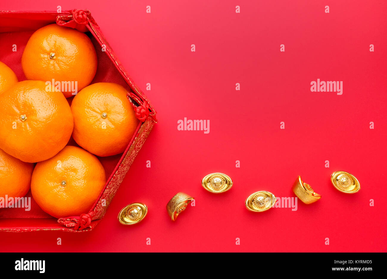 Group of orange tangerine in Chinese pattern tray with gold ingots on red table top. Chinese new year concep.Chinese Language ingot is wealthy Stock Photo