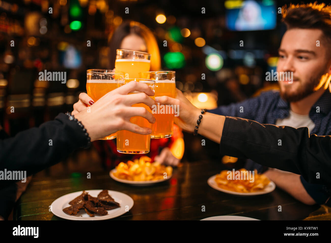 Fun company raised their glasses with beer in a sport bar, happy