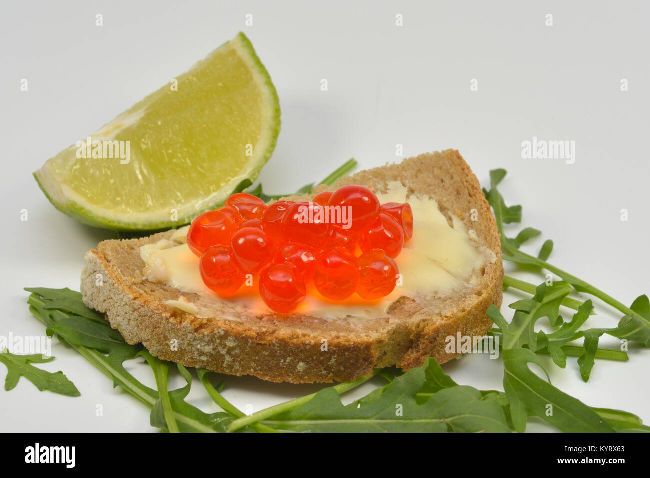 Fresh Salmon Raw Roe Sandwich (Red Caviar) on Rucola Leaves and Slice of Lime, isolated on white background Stock Photo