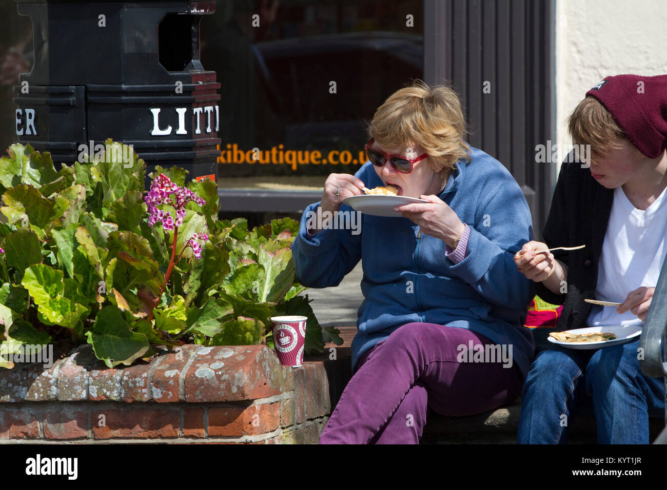 A couple outdoors sit on steps eating pancakes from paper plates Stock Photo