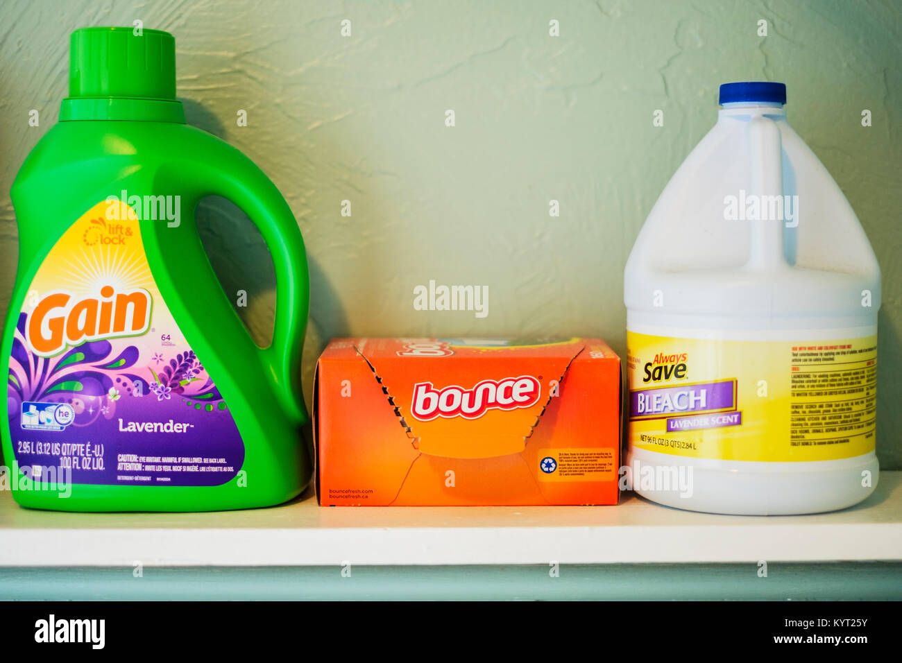 A laundry shelf containing Gain laundry detergent, a box of bounce dryer sheets, and a bottle of chlorine bleach. American, Oklahoma, USA. Stock Photo