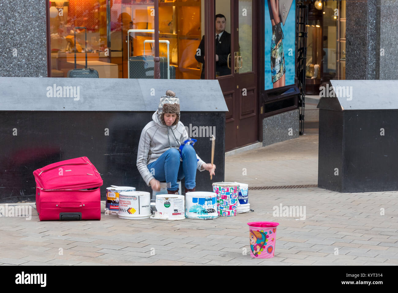 Woman on the streets of Leeds playing fake drums to make some money Stock Photo