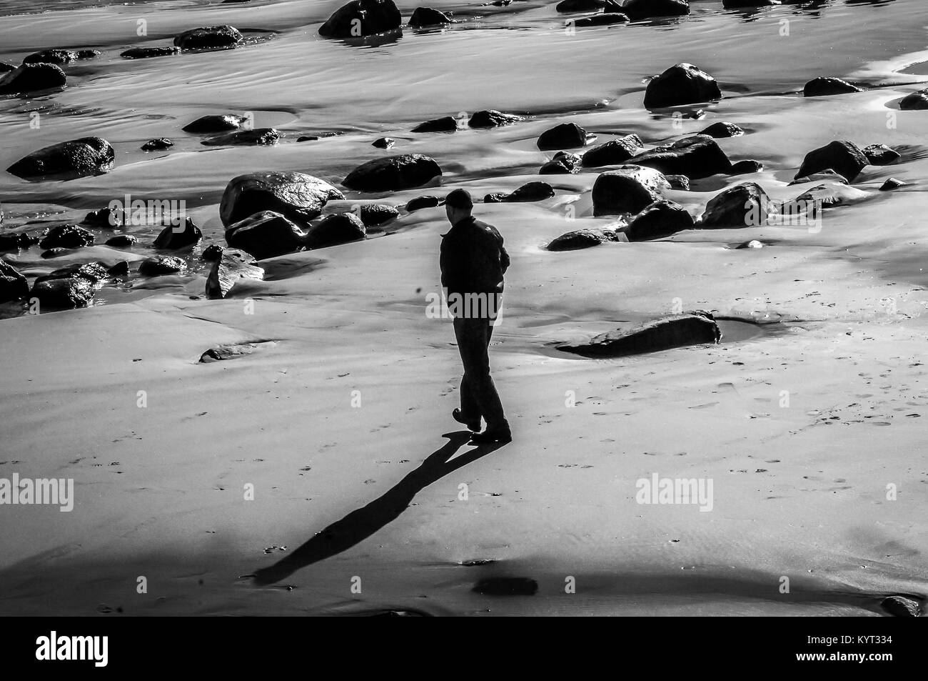 After a week of a Blizzard,and sub zero temperatures. This man takes a walk in the Sun on the beach. The forecast is for more cold,and snow tomorrow. Stock Photo