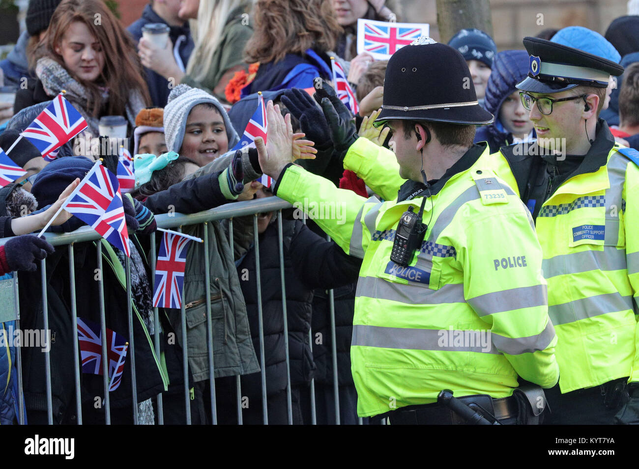 Police officers high five children as they await the arrival of the Duke and Duchess of Cambridge at the new Cathedral in Coventry during their visit to the city. Stock Photo