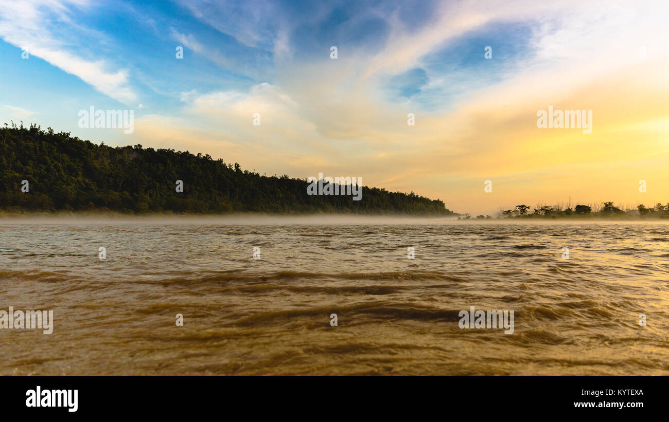 River Ganga / Ganges flowing in full force at Triveni Ghat, Rishikesh, Uttarakhand, India. Beautiful view around sunset/dusk/golden hour. Orange hues Stock Photo