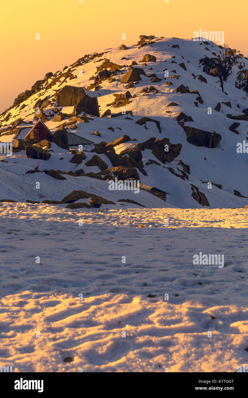 First rays of sun falling on a snow mountain called Triund in Mcleodganj,Dharamshala, Himachal pradesh, India at golden hour. Stock Photo