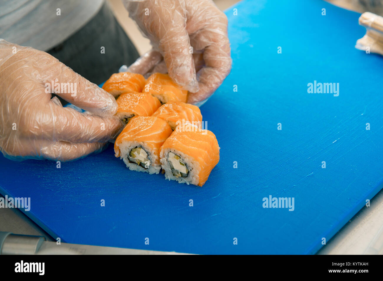 Chef hands putting sushi. Cook in gloves placing delicious sushi rolls