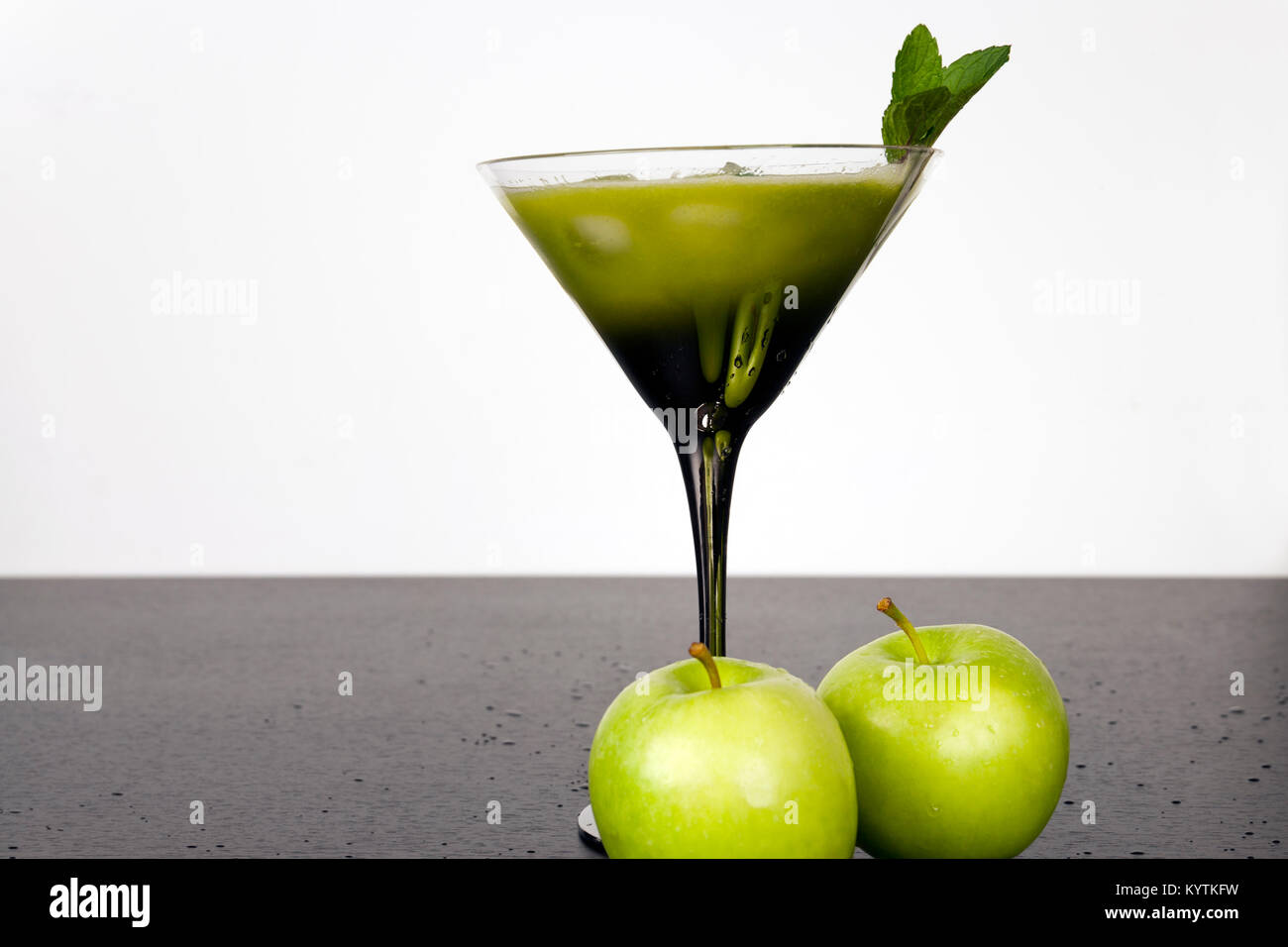 Green fruits and vegetables juiced in cocktail glass with a sprig of