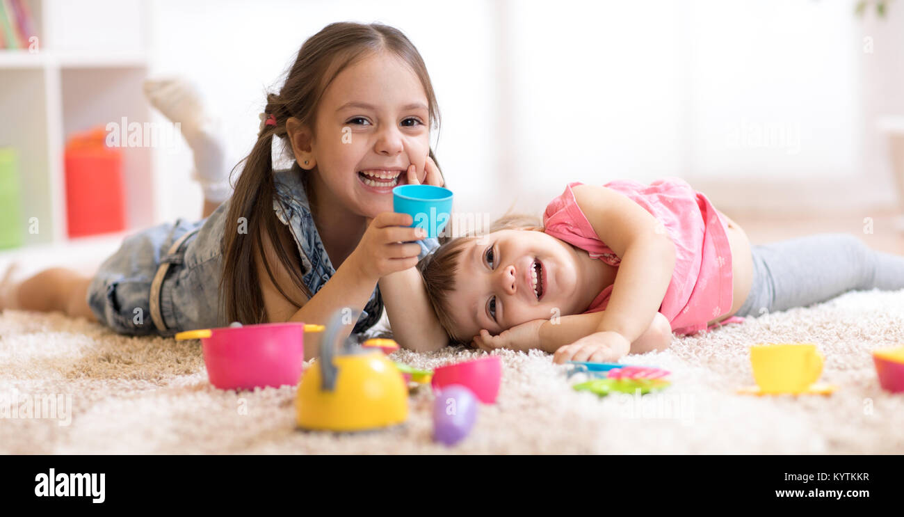Cute funny children girls playing with dishware toys at home Stock Photo