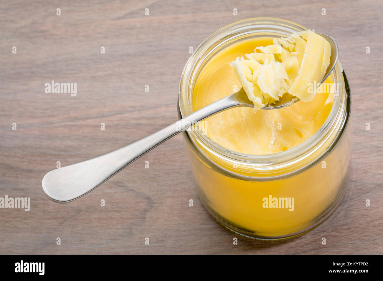 jar and tablespoon of ghee (clarified butter) on grained wood Stock
