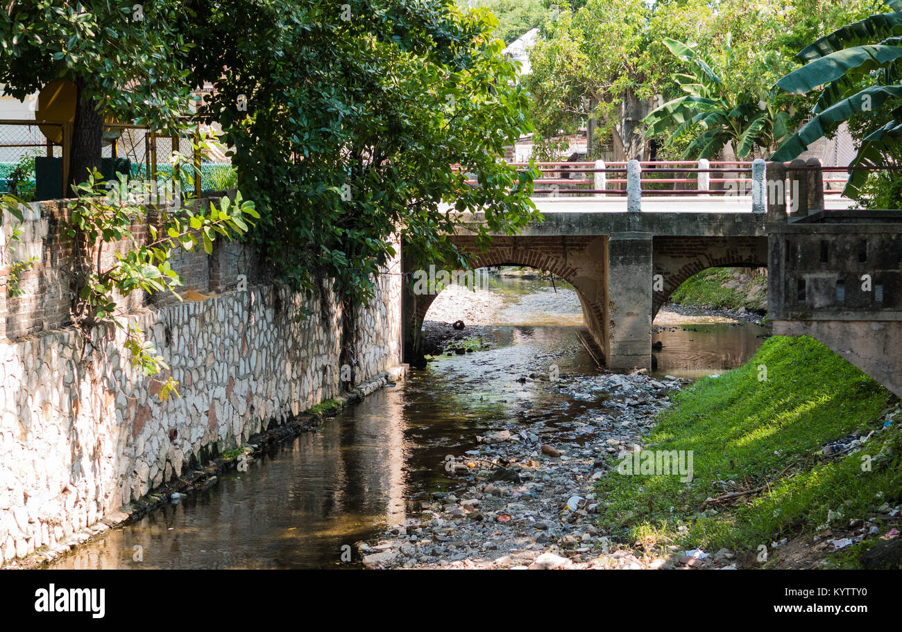 HOLGUIN, CUBA - AUGUST 31, 2017: Small bridge and canal in Cuba with visible litter everywhere. Stock Photo
