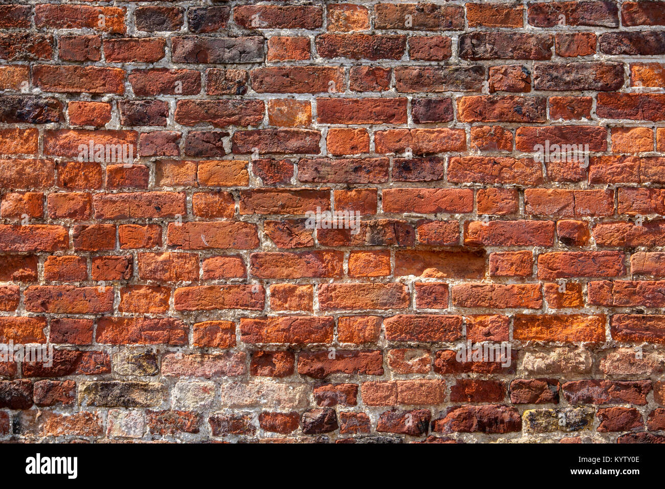 An old weathered, damaged, badly repaired red brick wall full frame
