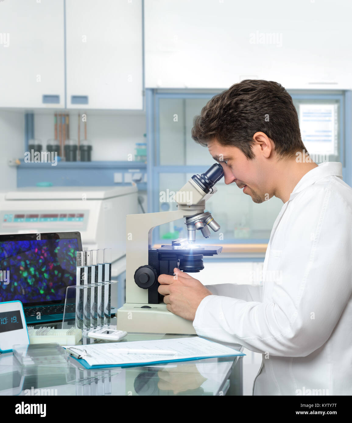Male scientist or tech works with microscope in modern research facility Stock Photo