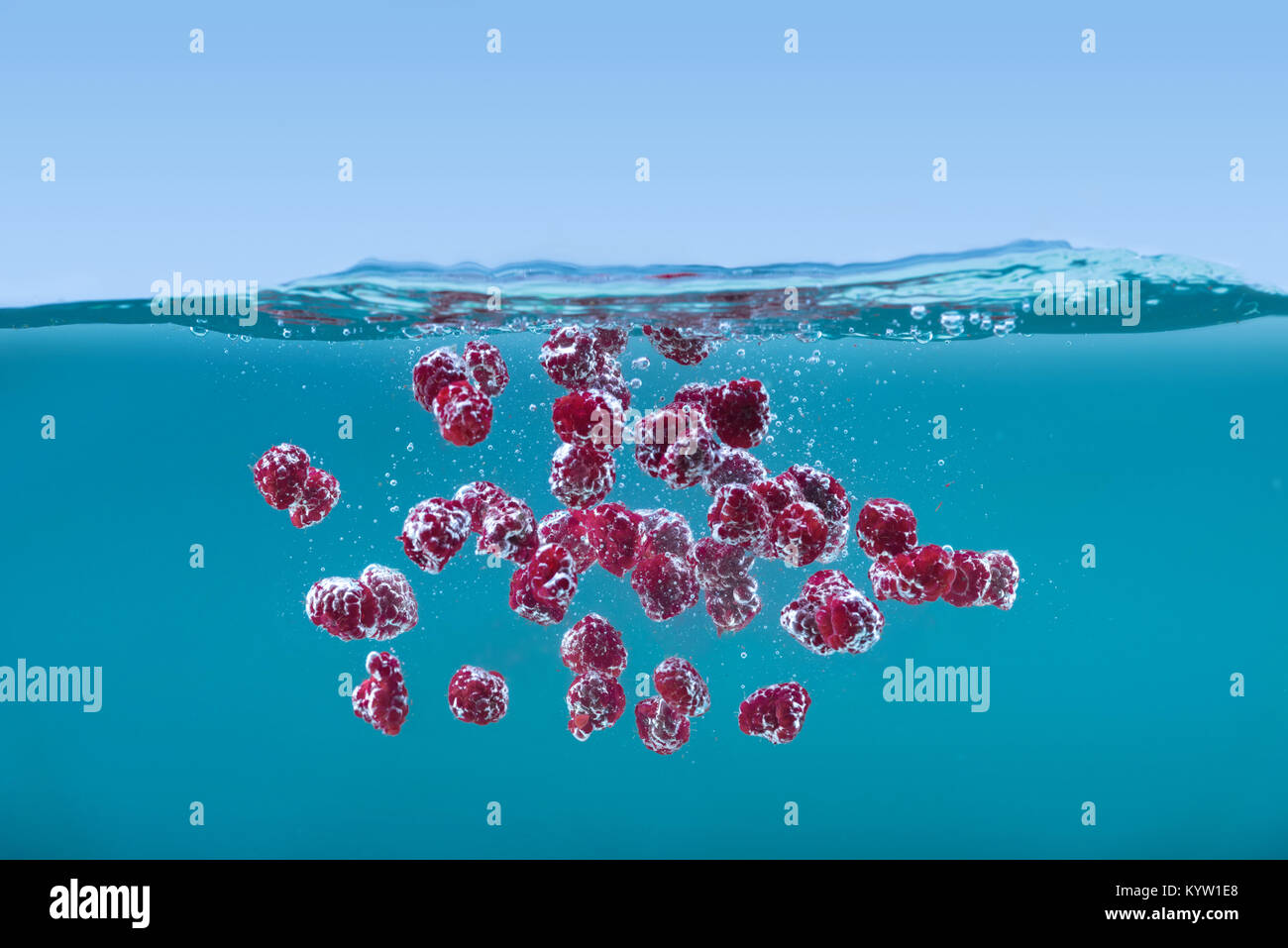 side view of ripe raspberries floating in water with bubbles and waves ...