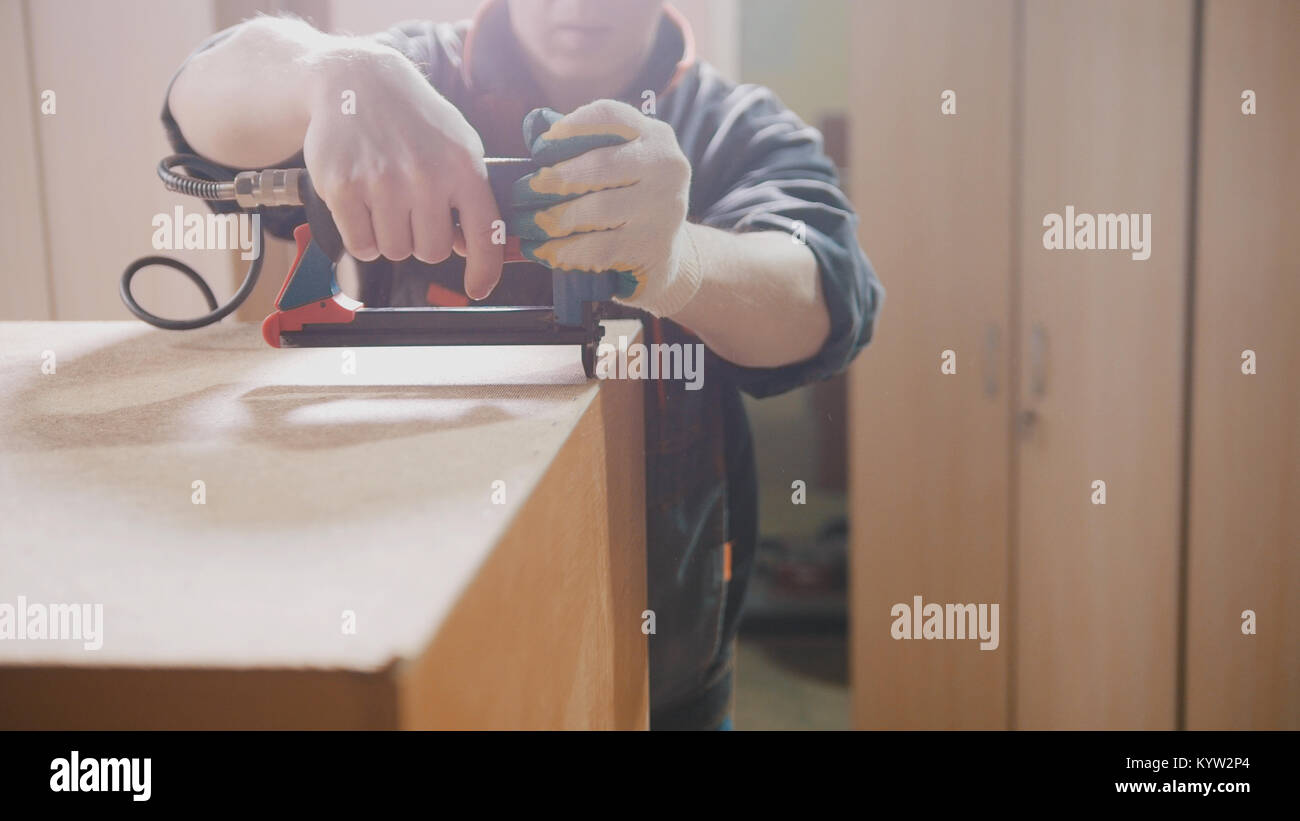 Carpenter working with an electric industrial stapler on the factory