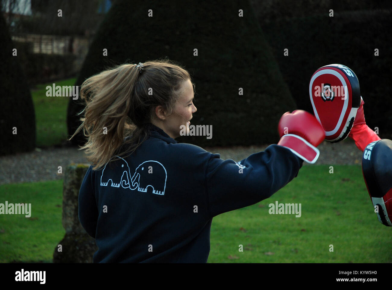 Attractive young woman practicing boxing outside throwing a punch Stock Photo