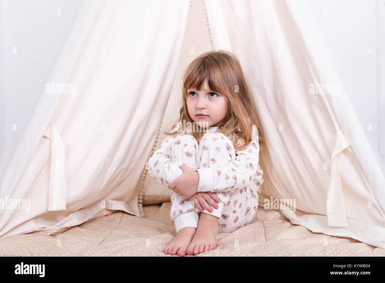 Small sad girl sits at a tent in pajamas and hugs her knees Stock Photo -  Alamy