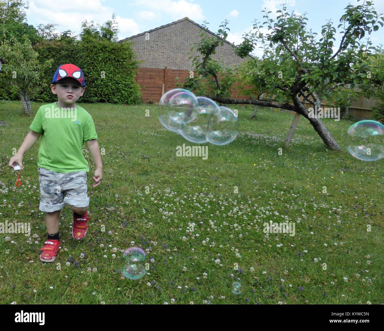 Young boy chasing bubbles in garden Stock Photo