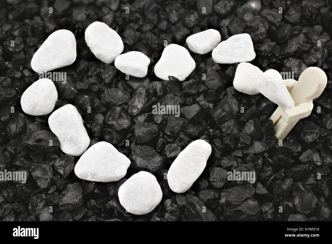 Wooden male completes a white pebble heart - symbol of working on love Stock Photo