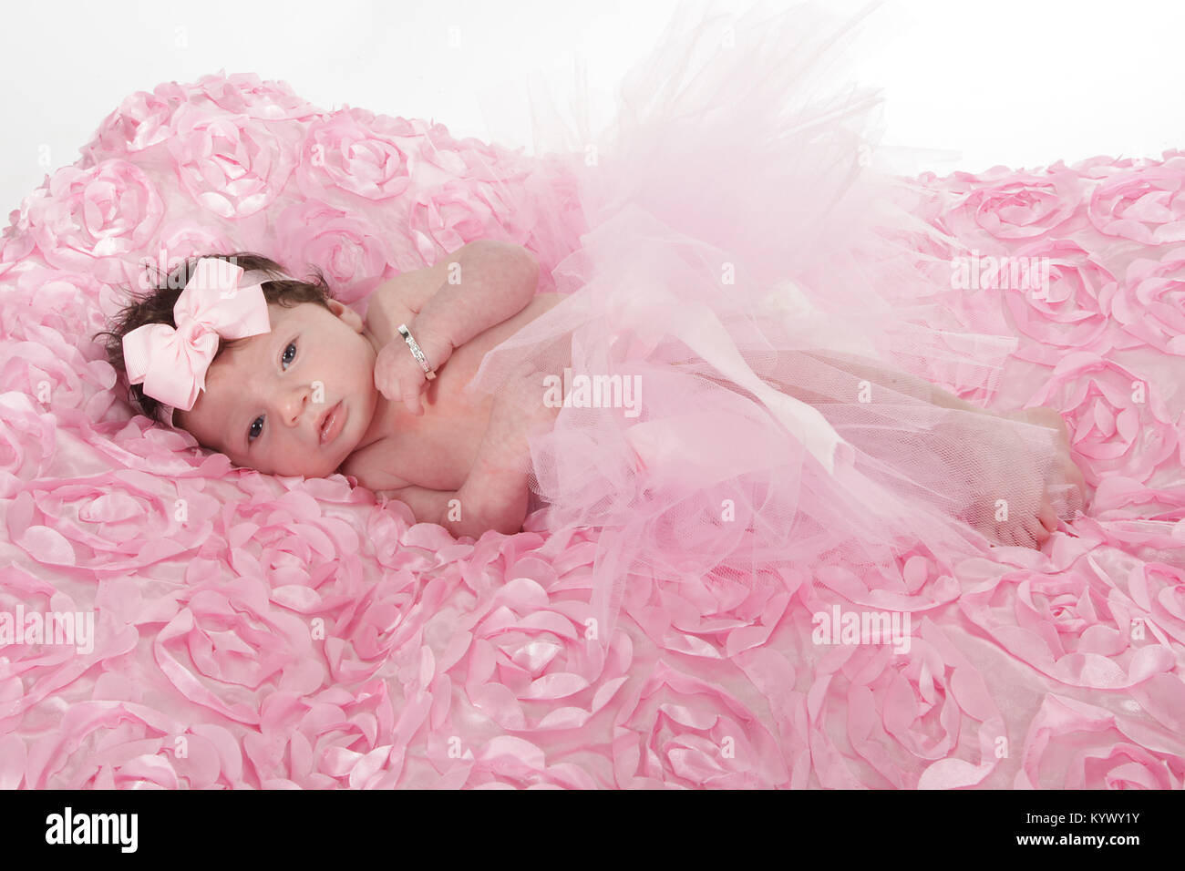 3 week old baby girl with lots of dark hair in too-too laying on rug Stock Photo