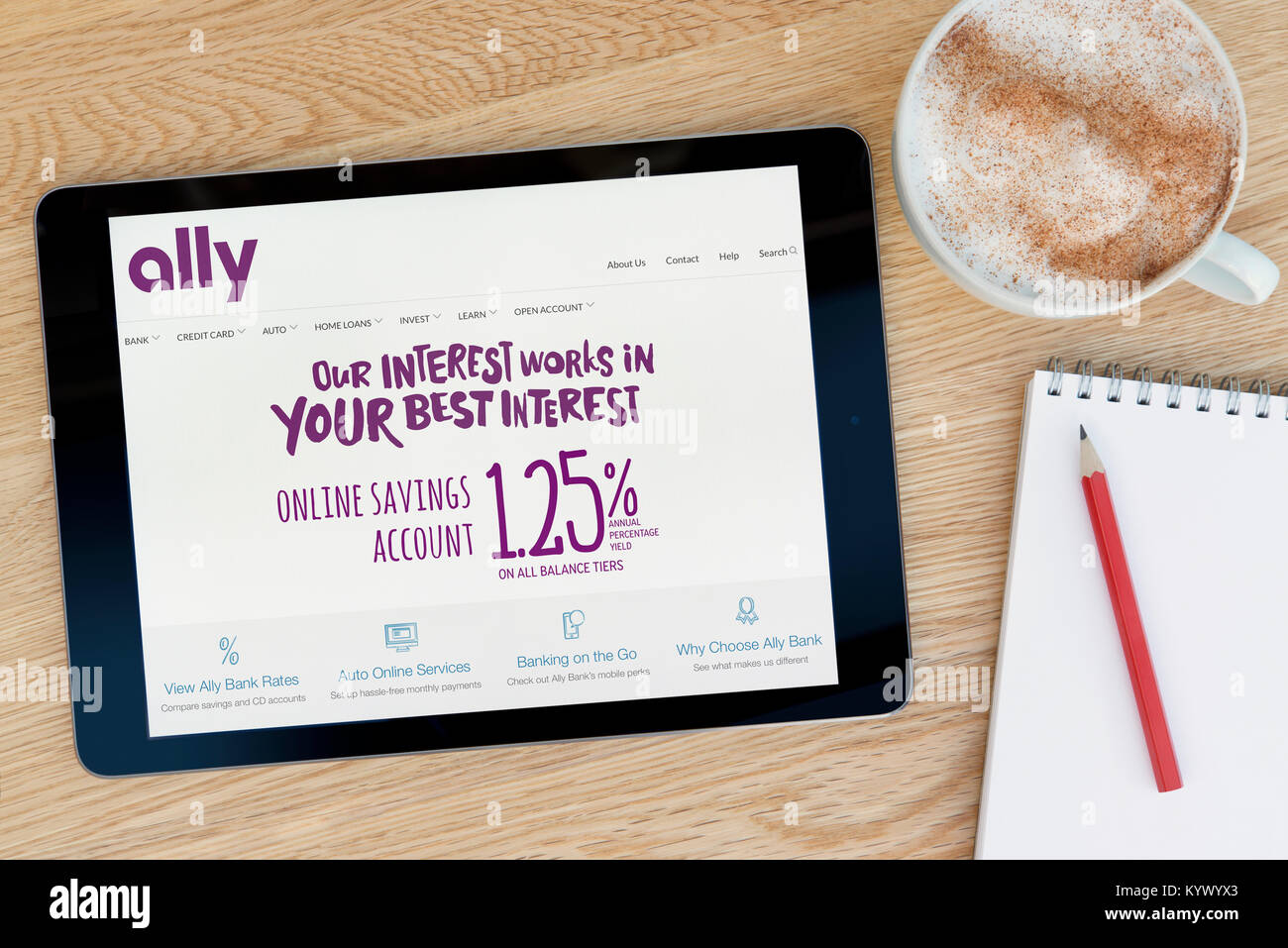The Ally Bank website on an iPad tablet, on a wooden table beside a notepad, pencil and cup of coffee (Editorial only) Stock Photo