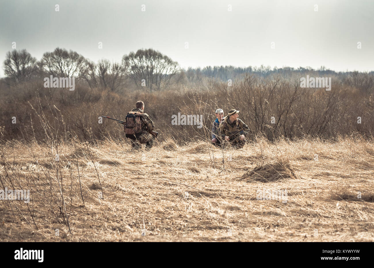 Hunting scene with hunters in rural field with dry grass during hunting season Stock Photo